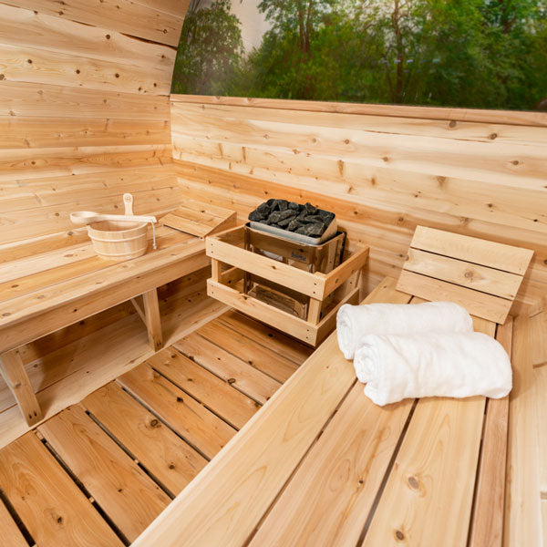 Interior of Leisurecraft luxury barrel sauna with wooden benches, sauna heater, and white towels