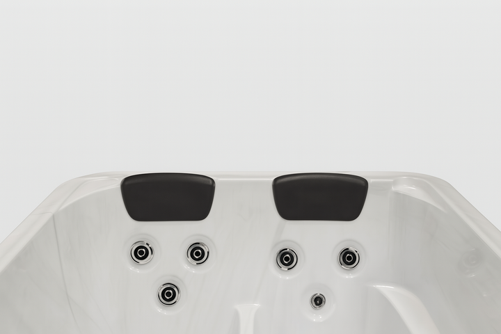 Luxury hot tub by Luxury Spa with white interior, dual black headrests, and multiple water jets
