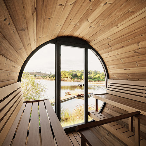 Interior view of luxury outdoor barrel sauna with wooden benches and large window overlooking lake