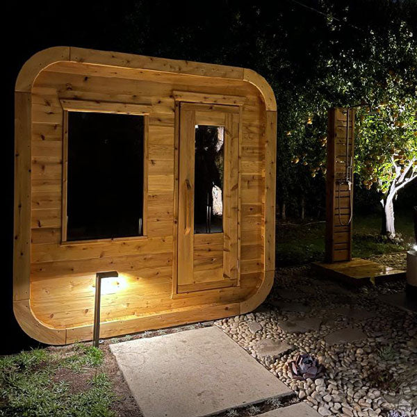 Leisurecraft traditional wooden outdoor luxury sauna illuminated at night in garden setting