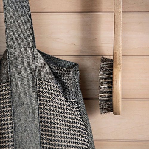 Natural bath brush for sauna hanging on a wooden wall next to a fabric bag