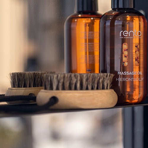 Rento natural nail brush for spa with wooden handle next to massage oil bottles