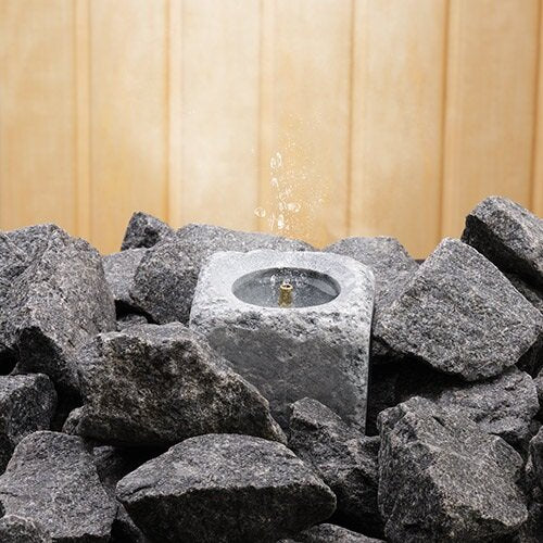 Hukka Finnish sauna soapstone accessory cube steam water fountain nestled among sauna stones