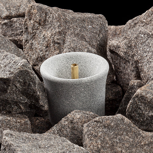 Hukka sauna fountain and diffuser in gray stone cup with brass nozzle surrounded by sauna stones