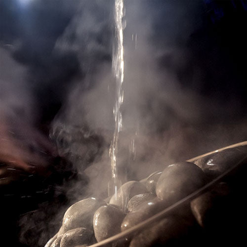HUUM olivine diabase sauna stones with steam rising as water is poured over them