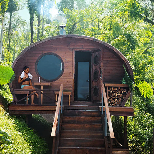 Outdoor home sauna kit by SaunaLife featuring a wooden traditional sauna cabin in a lush forest setting
