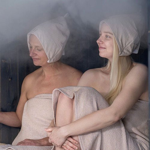Two women wearing Rento Kenno sauna hats enjoying a steam sauna experience together