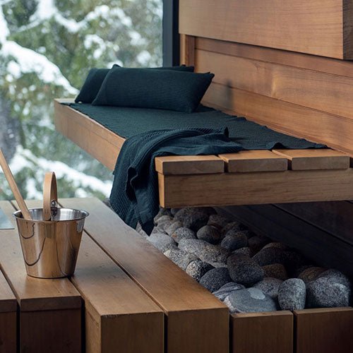 Rento Kenno sauna pillow placed on a wooden sauna bench with stones and a sauna bucket nearby