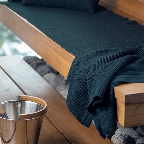 Rento Sauna Seat Cover in Dark Color on a Wooden Bench for Comfortable Sauna Experience