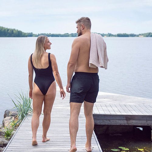 Couple walking by the water, showcasing the Rento Kenno spa towel draped over the man's shoulder
