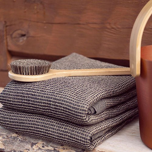 Rento Kenno spa towel in a folded stack with a wooden brush on a rustic surface