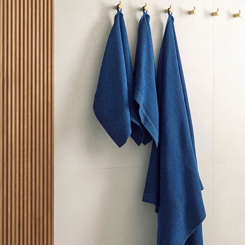 Rento Kenno spa towel in navy blue hanging on hooks for a stylish bathroom accessory