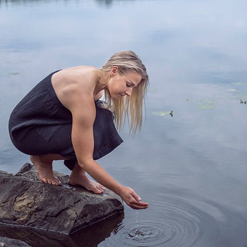 Rento Kenno waist towel worn by a woman by a serene lake while crouching down