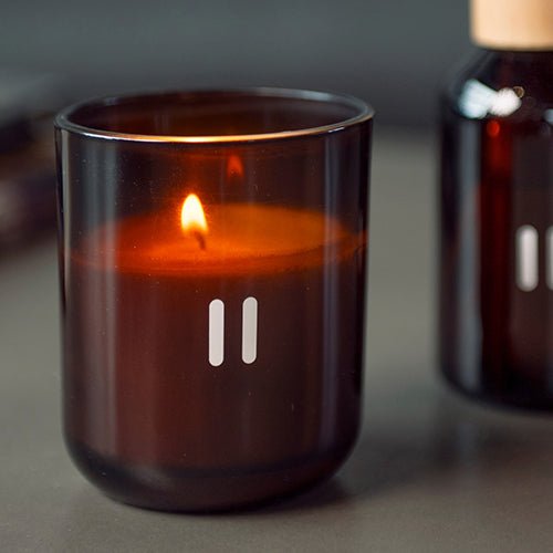 Rento luxury soy scented candle in amber glass jar with warm glowing flame for a cozy atmosphere