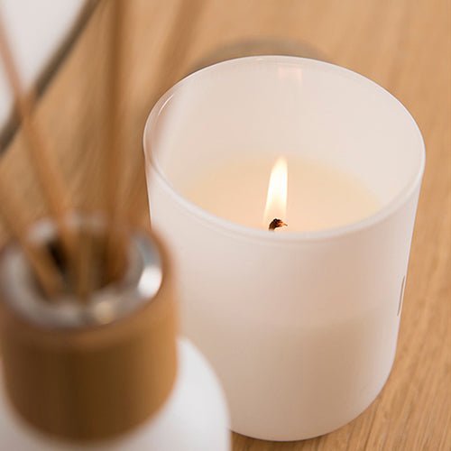 Rento luxury soy scented candle in white container with a warm flame for a cozy ambiance