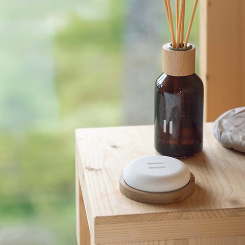 Rento stone diffuser with a minimalistic design placed alongside a fragrance bottle on a wooden table