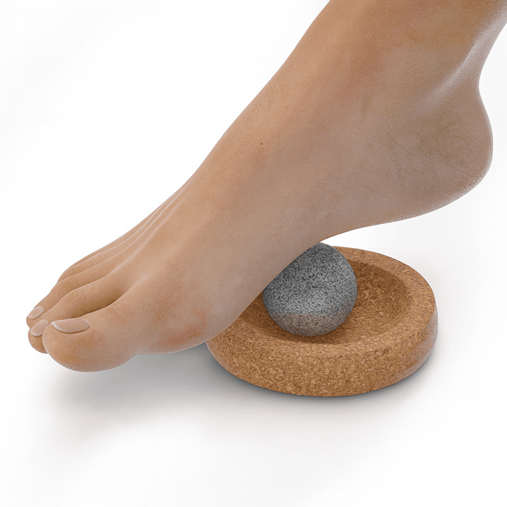 Hukka sauna massage sphere on a cork base with a foot pressing down for relaxation