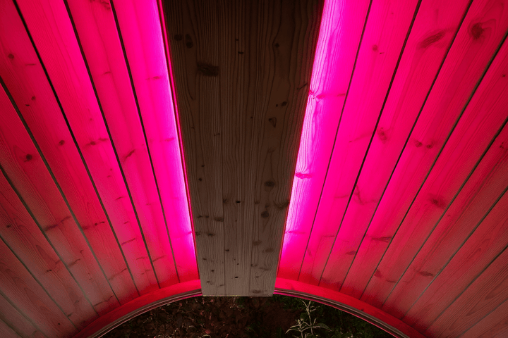 Sauna RGB LED lighting kit illuminating wooden sauna interior with vibrant pink hues