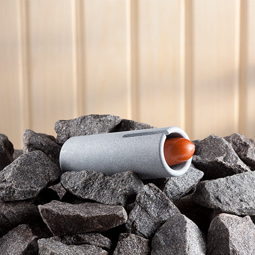 Hukka Finnish sauna sausage cooker stone cylinder accessory resting on sauna rocks with sausage inside