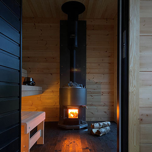 Narvi wood-burning sauna stove inside wooden sauna room with glowing fire and stacked logs