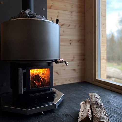 Narvi wood-burning sauna stove with glowing fire and logs on wooden floor in sauna room
